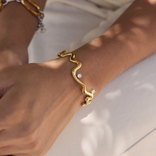 Thalia Squiggle Cuff on a wrist featuring three round crystals, crafted from gold plated stainless steel.