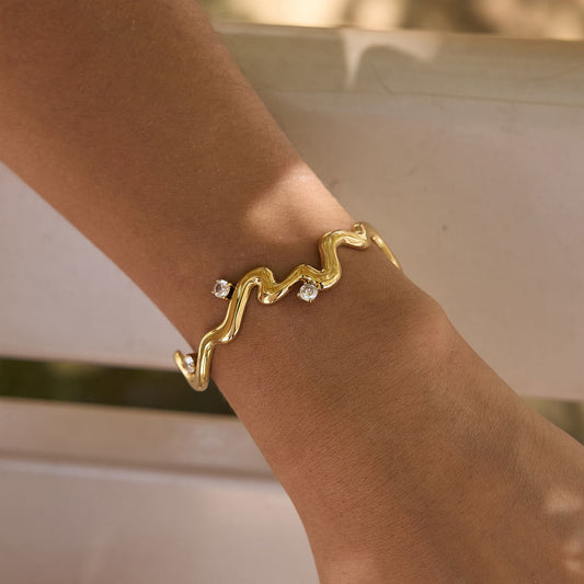 Thalia Squiggle Cuff in gold plated stainless steel with round crystals, worn on a wrist.