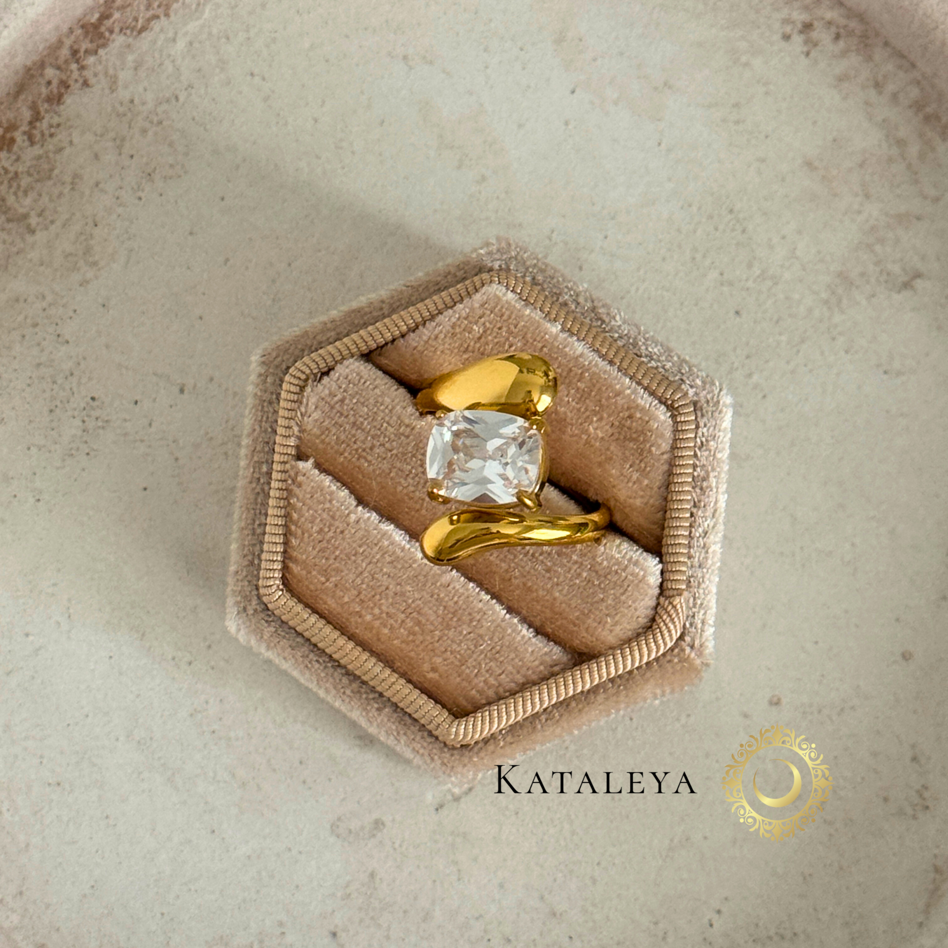 Elegant Twist Diamond Ring displayed on a beige hexagonal ring box, featuring a clear diamond and modern gold design.