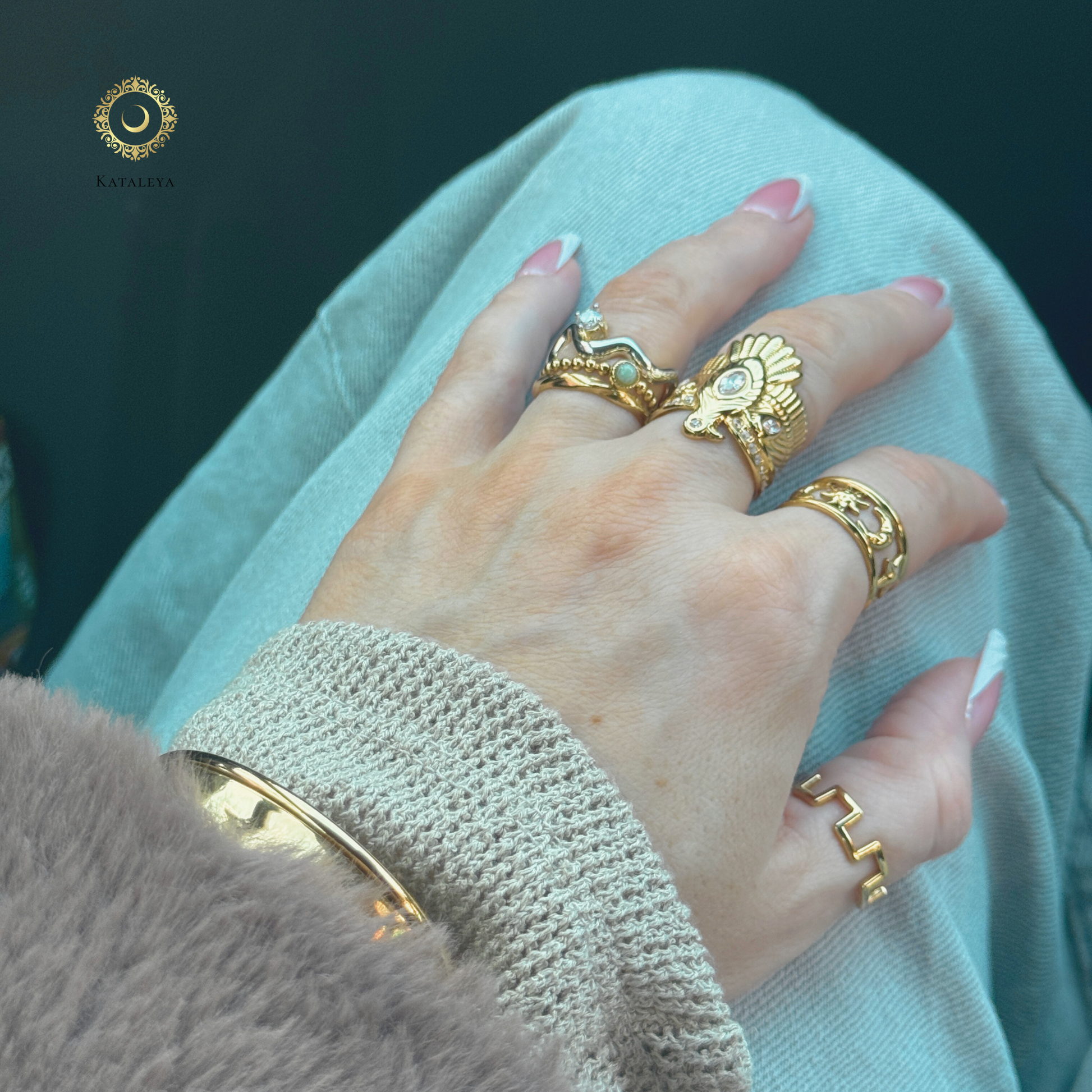 A hand adorned with various gold rings including the Nekhbet Eagle Statement Ring, showcasing style and elegance.