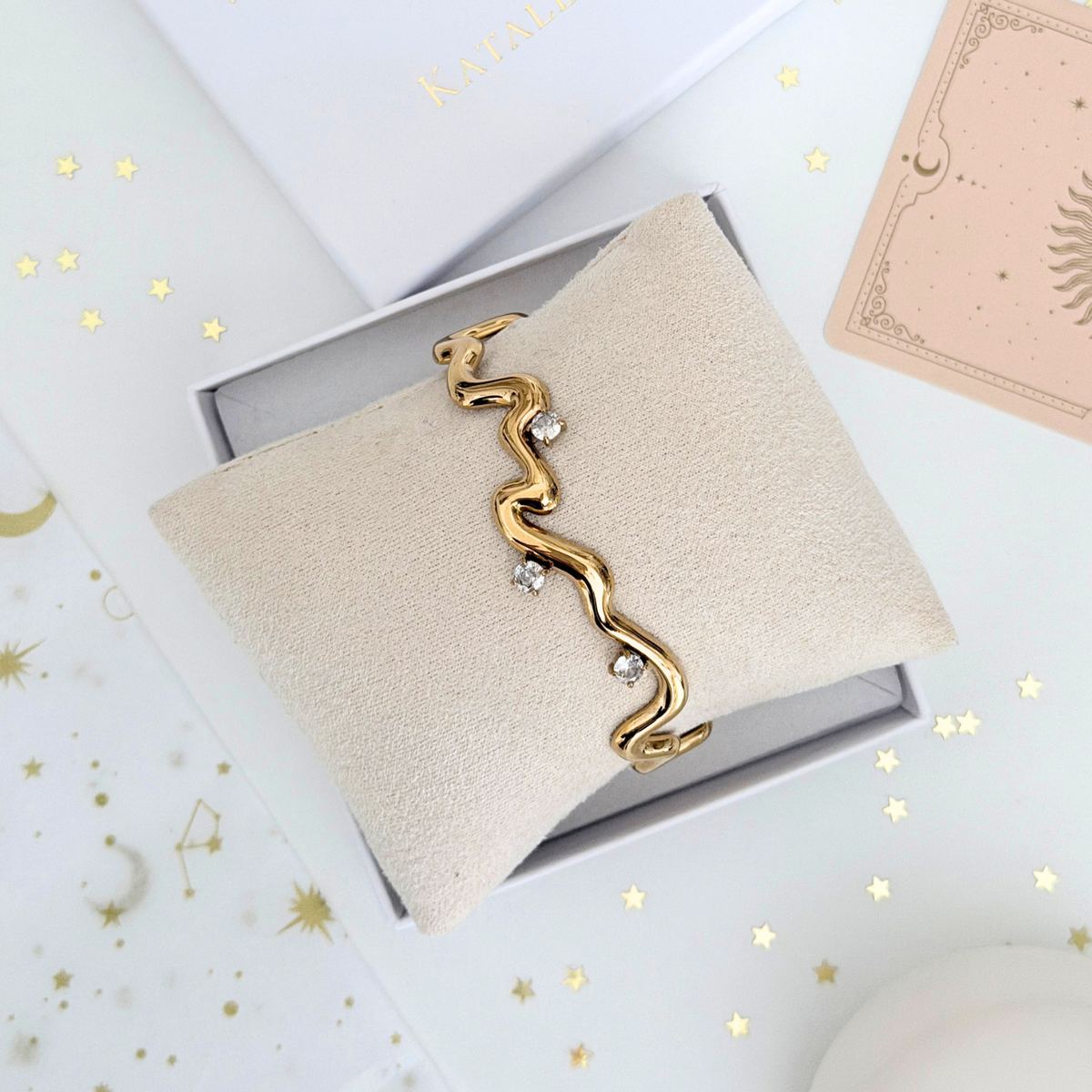 Thalia Squiggle Cuff displayed on a beige cushion, featuring a hand-drawn zigzag design and three round crystals.