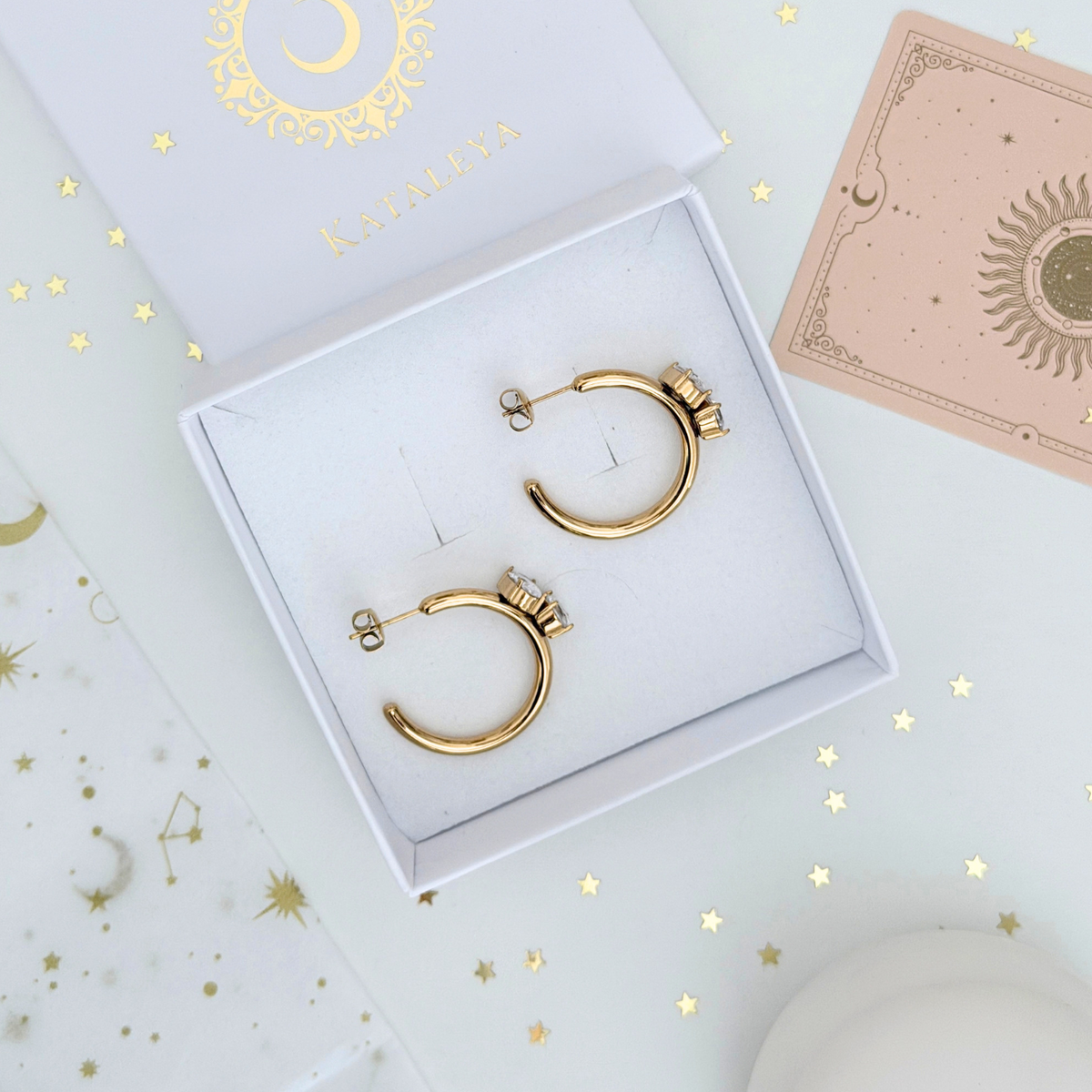 Vega Crystal Hoops displayed in a jewelry box with gold plated design and sparkling crystals, perfect for any occasion.