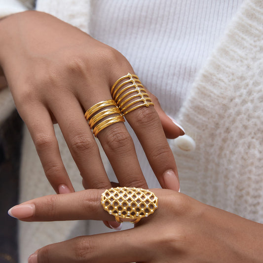Model showcasing the Orla Cage Ring among gold stack rings on her fingers, highlighting elegant jewelry design.