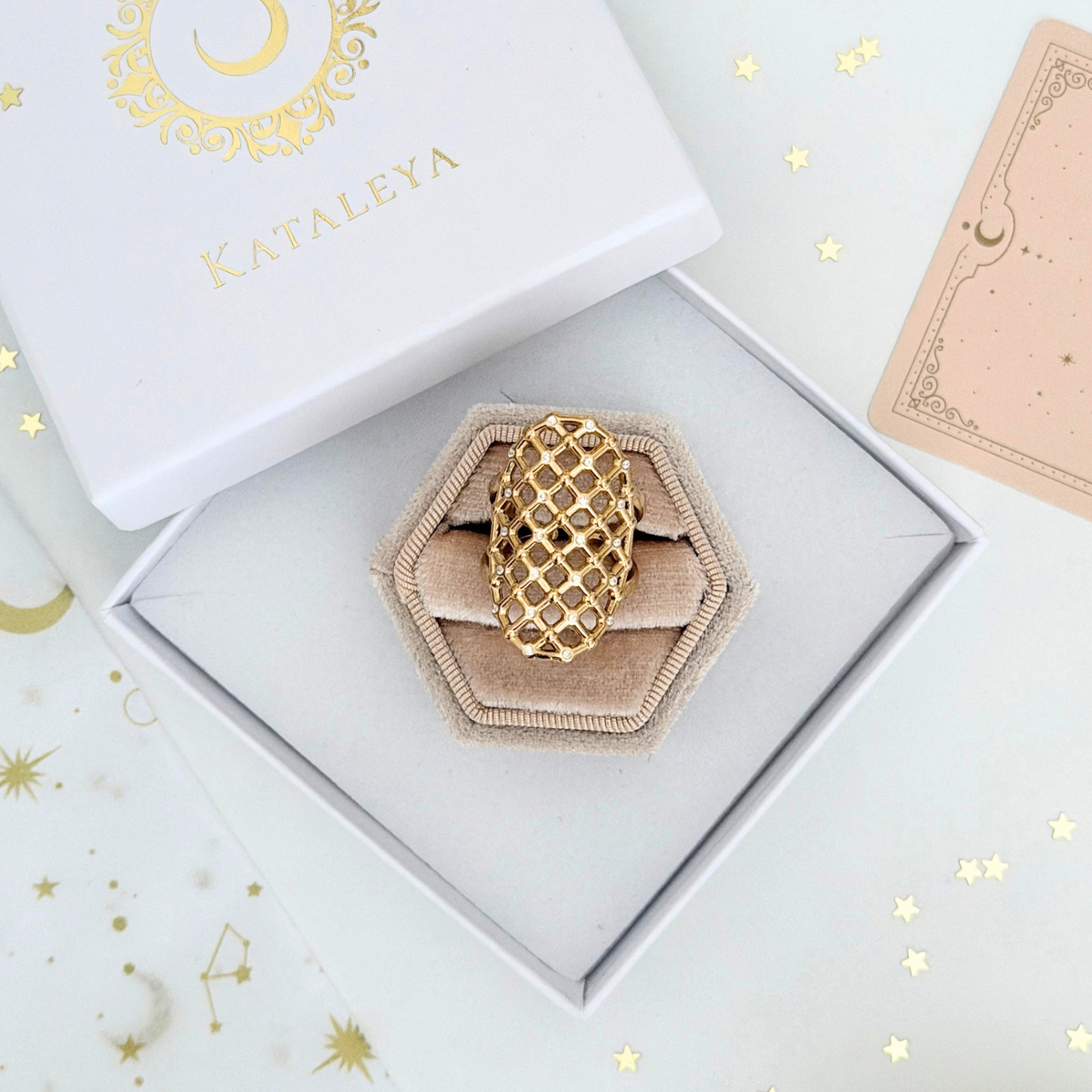 Vela Lattice Ring displayed in a hexagonal box with gold bars and cubic zirconia accents.