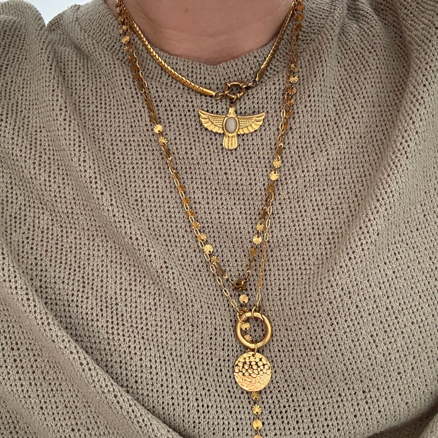 Coin Carabiner Necklace showcasing layered gold chains and unique pendants on a textured sweater.