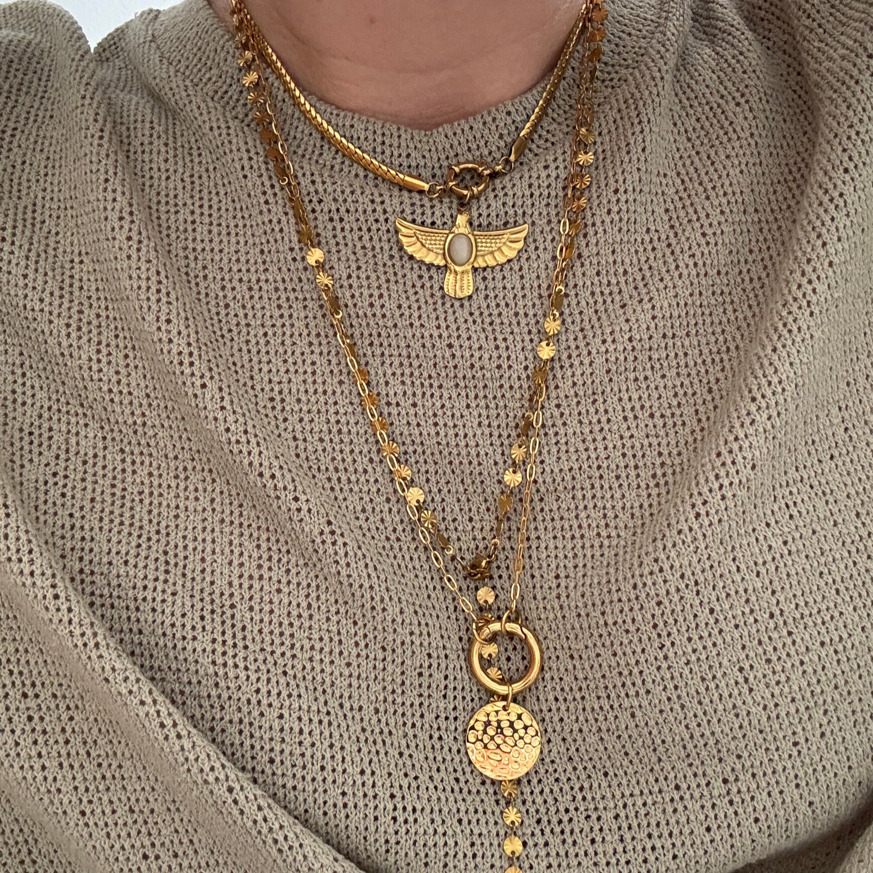 Coin Carabiner Necklace showcasing layered gold chains and unique pendants on a textured sweater.