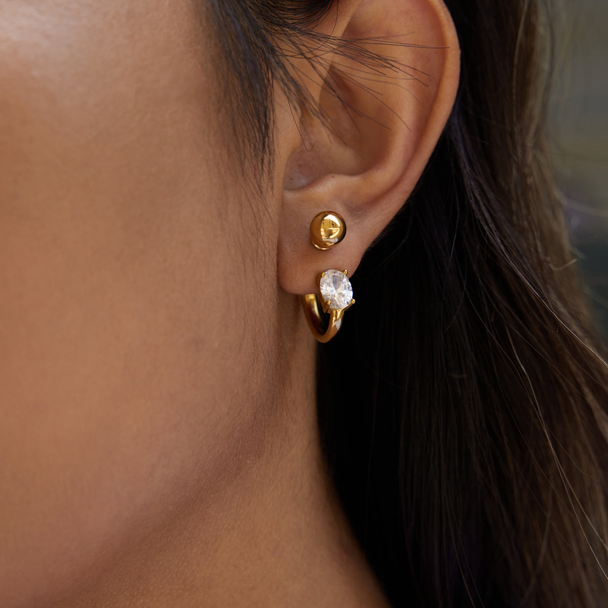 Gold crystal hoop earrings featuring a cubic zirconia stone, woman wearing jewelry in elegant style.
