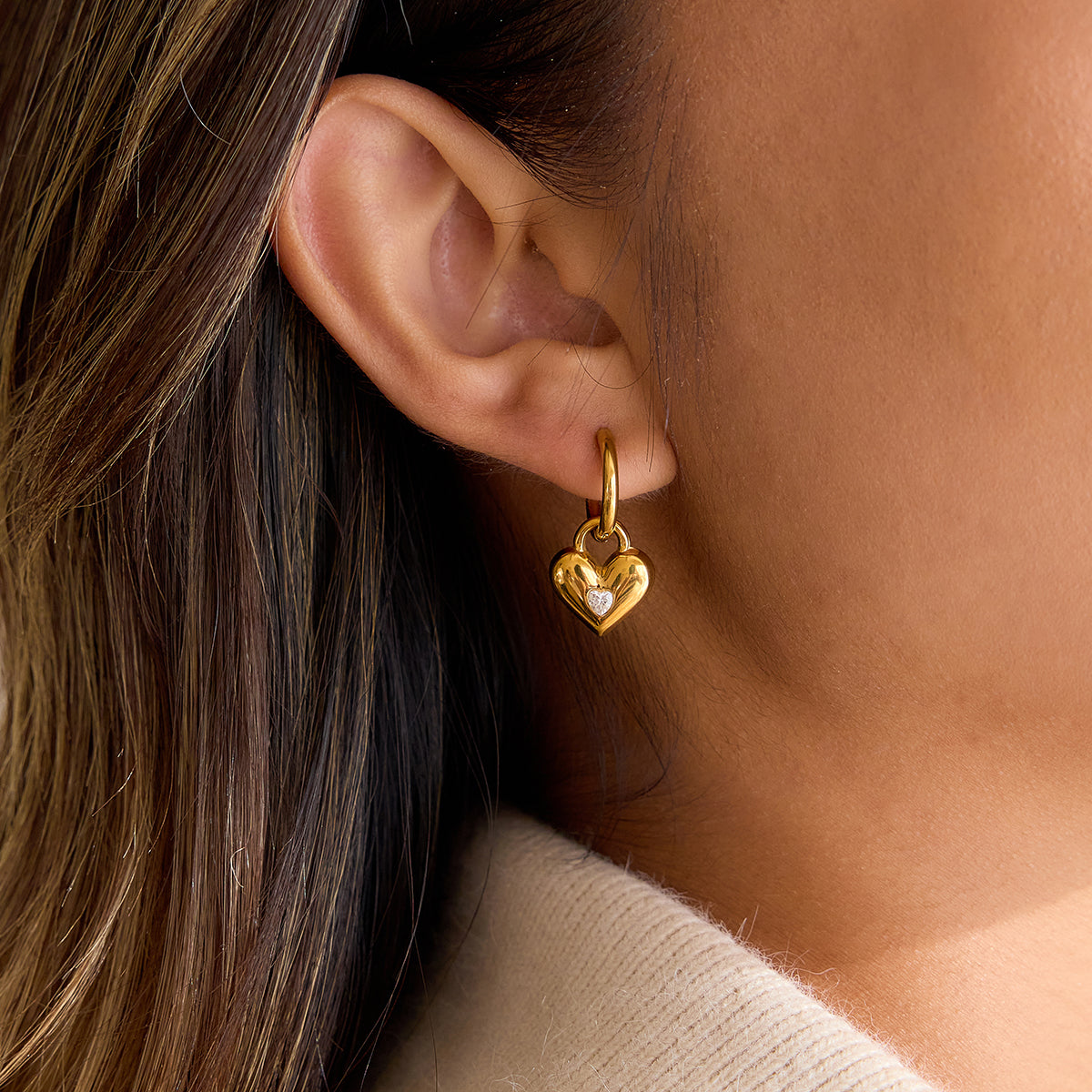 Cupid Hoop Earrings featuring a gold heart charm with cubic zirconia, worn on a model's ear.