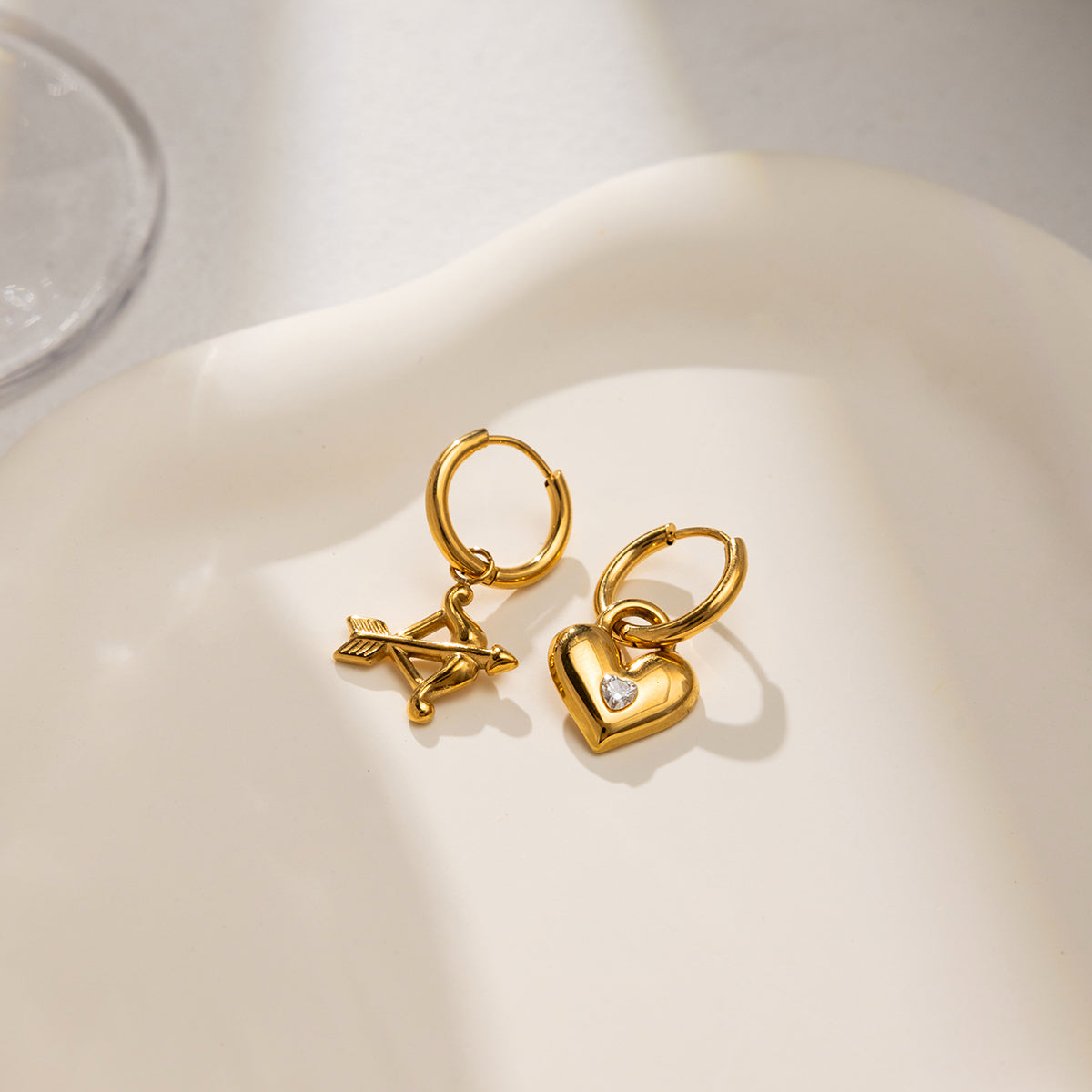 Cupid hoop earrings featuring gold heart and arrow charms, charming and playful jewelry design.