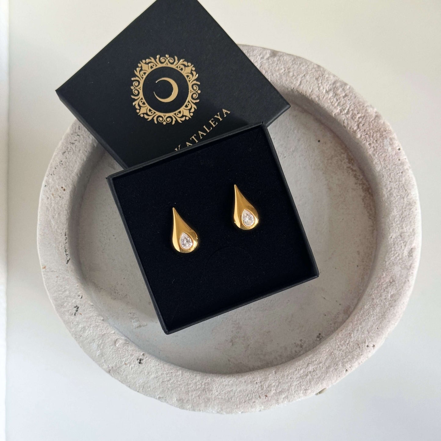 Classic Pear Cut CZ Stud Earrings displayed in a black box on a decorative stone plate.