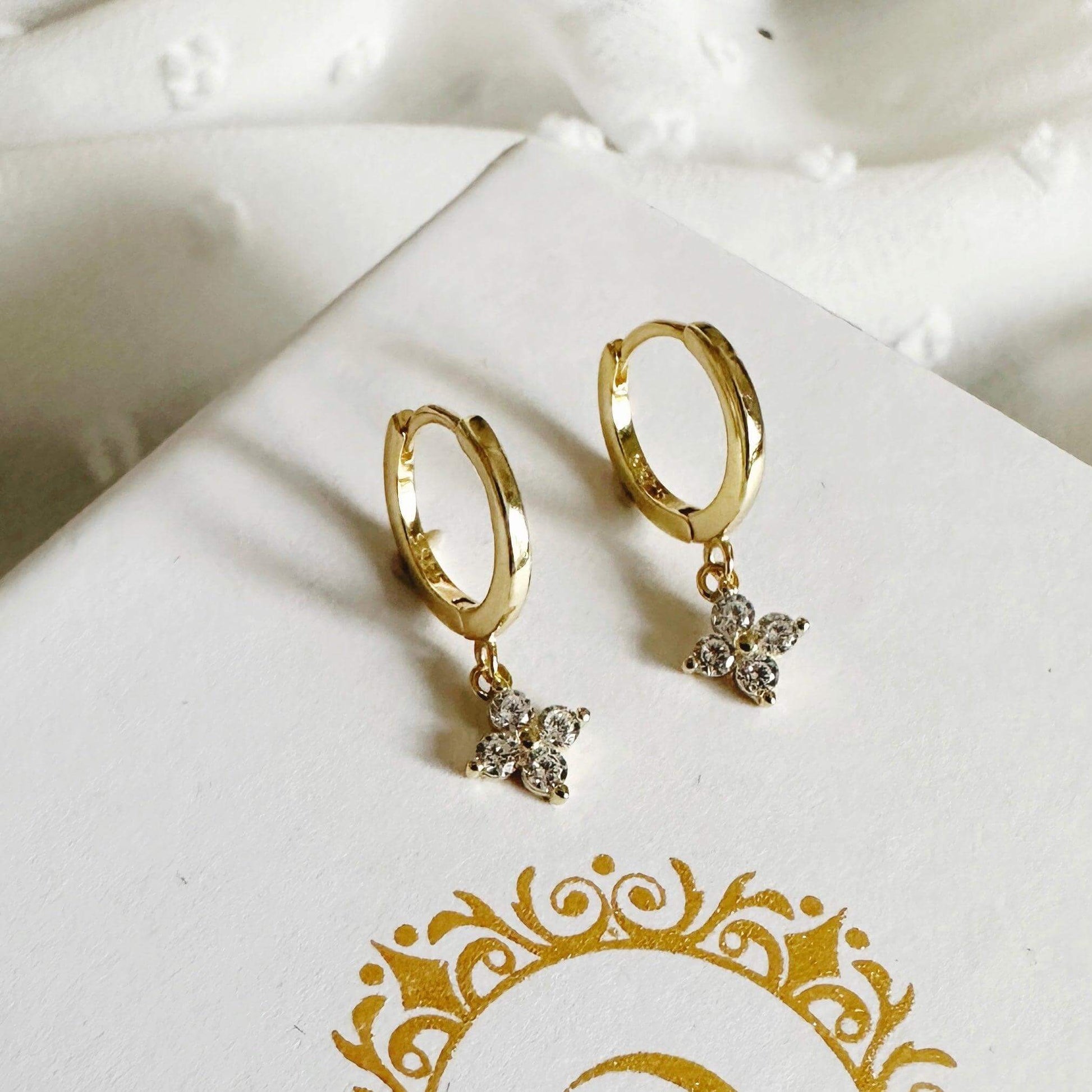 Diana Huggie Gold Earrings featuring dangling zircon flowers in gold, available from Kataleya.