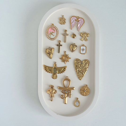 Collection of gold charms on a white trinket tray by Kataleya Jewellery on a white bakcground