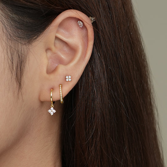 Diana Gold Earrings Set displayed on a model's ear, featuring gold flower studs and huggie hoops with CZ crystals.