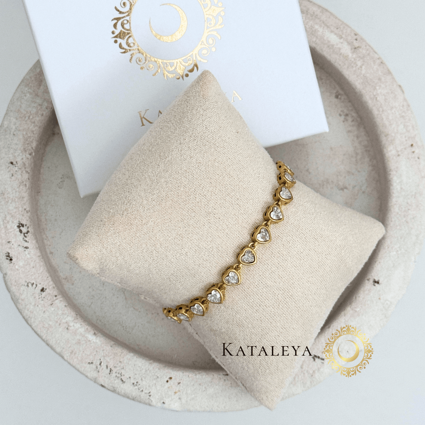 Heart Tennis Bracelet displayed on a cushion, featuring shimmering heart-shaped cubic zirconia stones in gold.