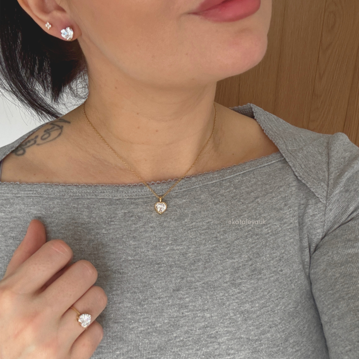 Woman wearing a Valentina Gold Heart Necklace alongside earrings and a ring, showcasing elegant jewelry style.