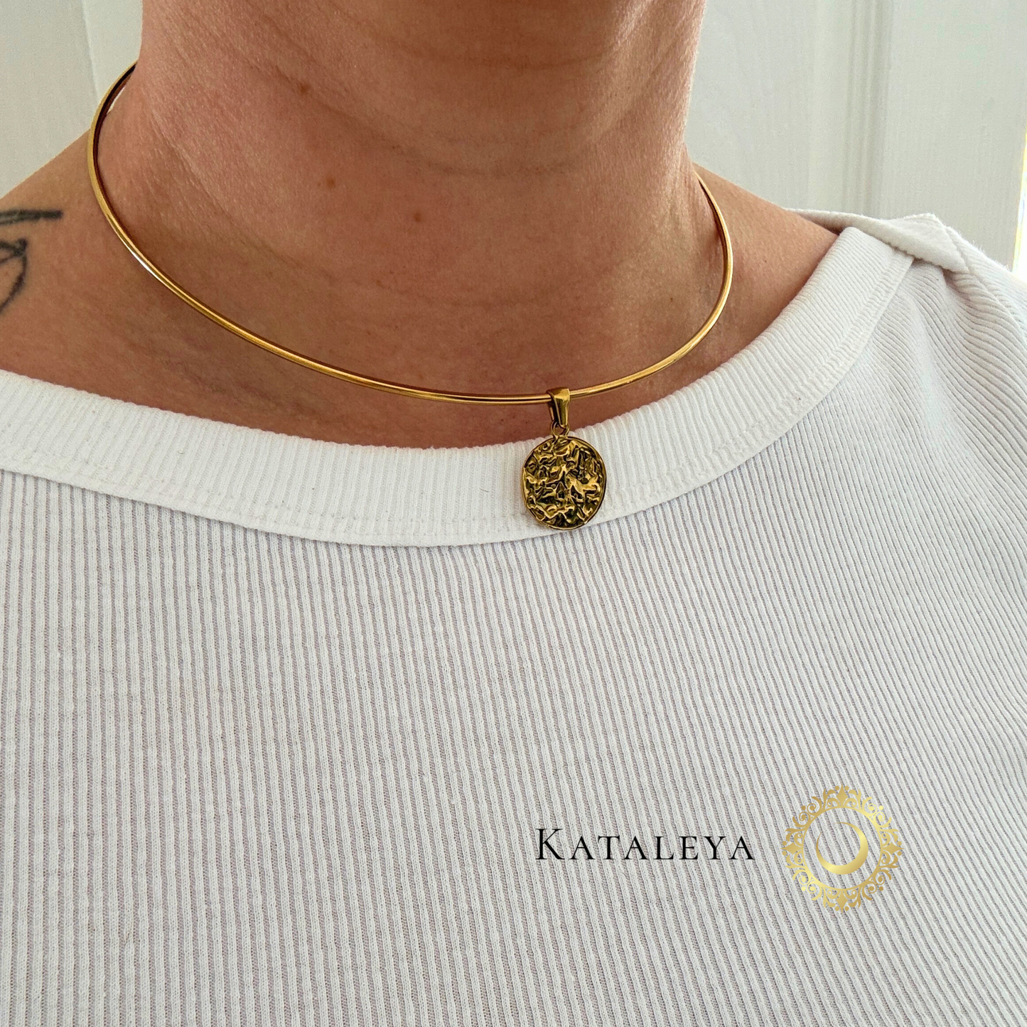 Minimalist wire choker worn with a charm, featuring a sleek design and elegant finish, perfect for layering or solo wear.