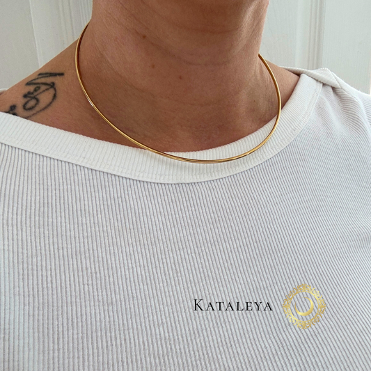 Person wearing a gold necklace with 'Kataleya' branding on a light background