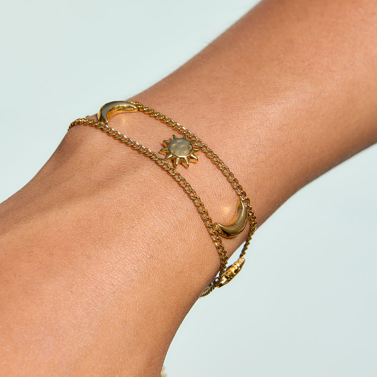 Celestial Harmony Bracelet on a wrist, featuring sun and moon charms in gold for waterproof and tarnish-free elegance.