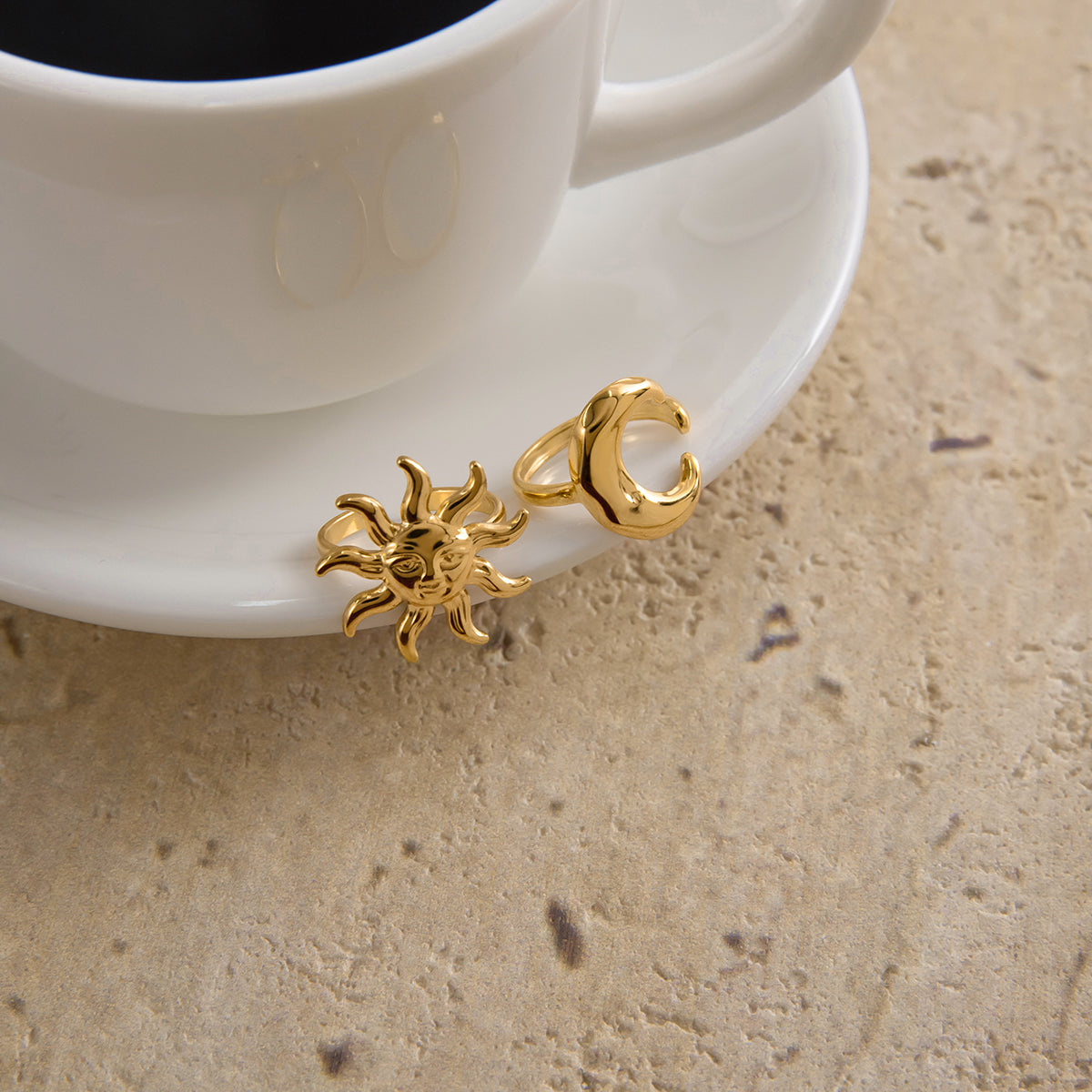 Chunky Gold Moon Ring and Chunky Gold Sun Ring alongside a cup, symbolizing transformation and feminine energy.
