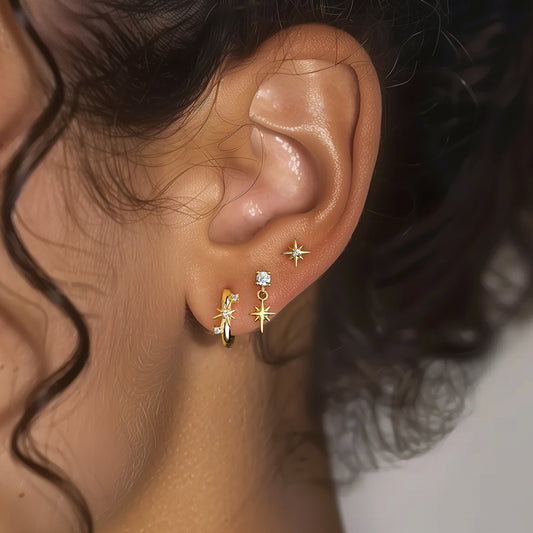 Close-up of an ear wearing gold star-shaped earrings - Celestial Star Gold Earrings Set - with a blurred background  Kataleya Jewellery