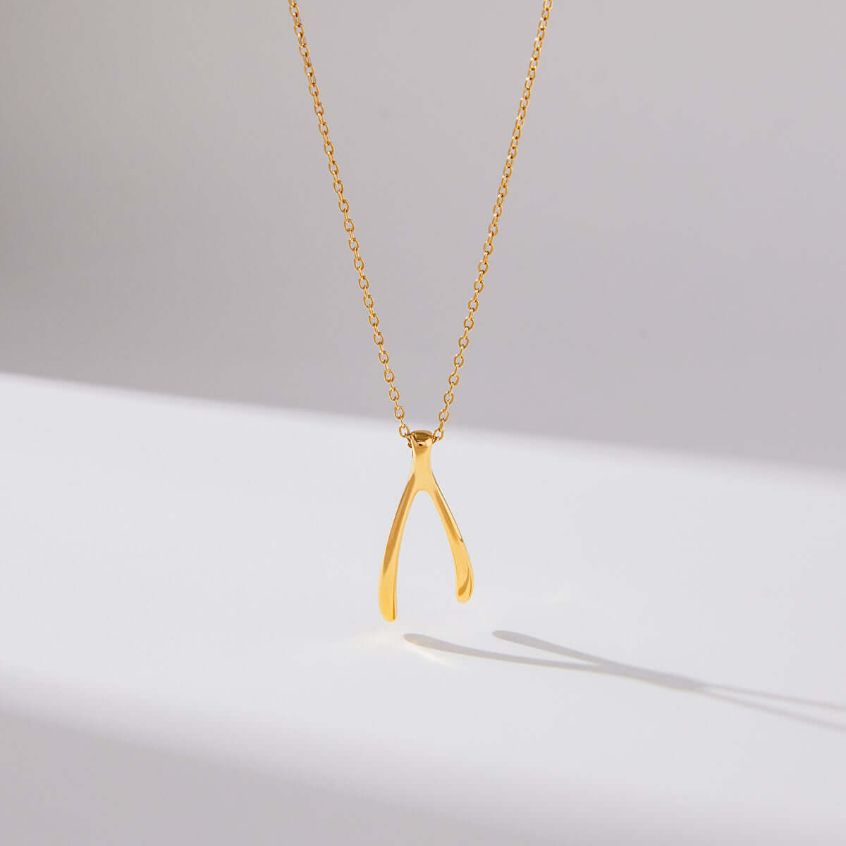 Gold Wishbone Pendant Necklace hanging on a dainty chain, showcasing a polished and minimal design.
